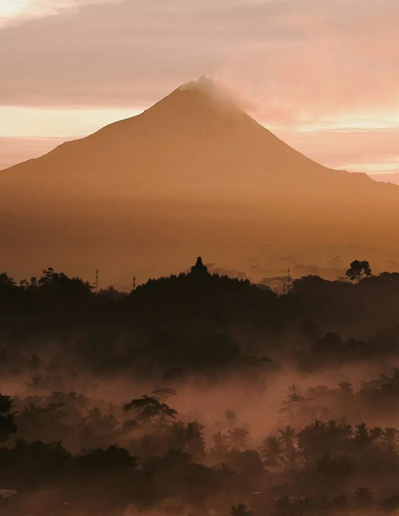 Borobudur Temple stupas in warm sunset light with mist rolling into the Kedu Valley
